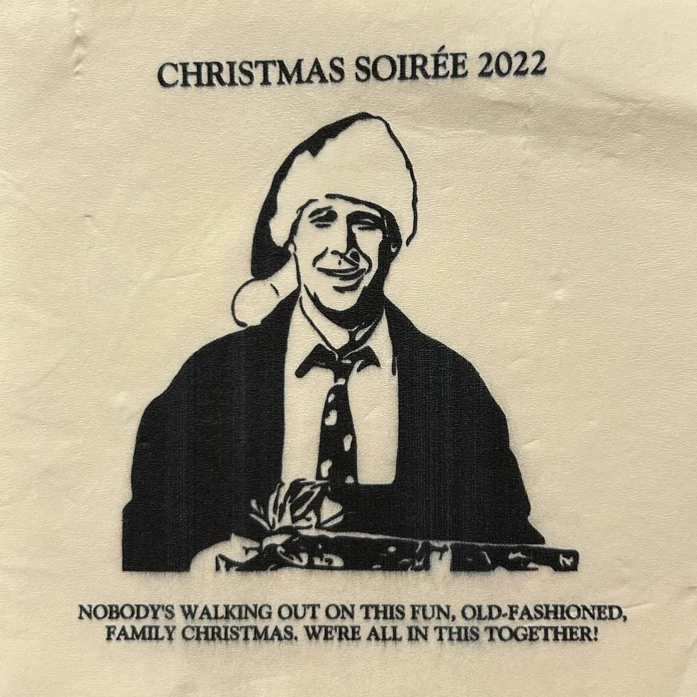 2022 napkin: Christmas Soirée 2022, with the line “Nobody’s walking out on this fun, old-fashioned family Christmas. We’re all in this together!”
